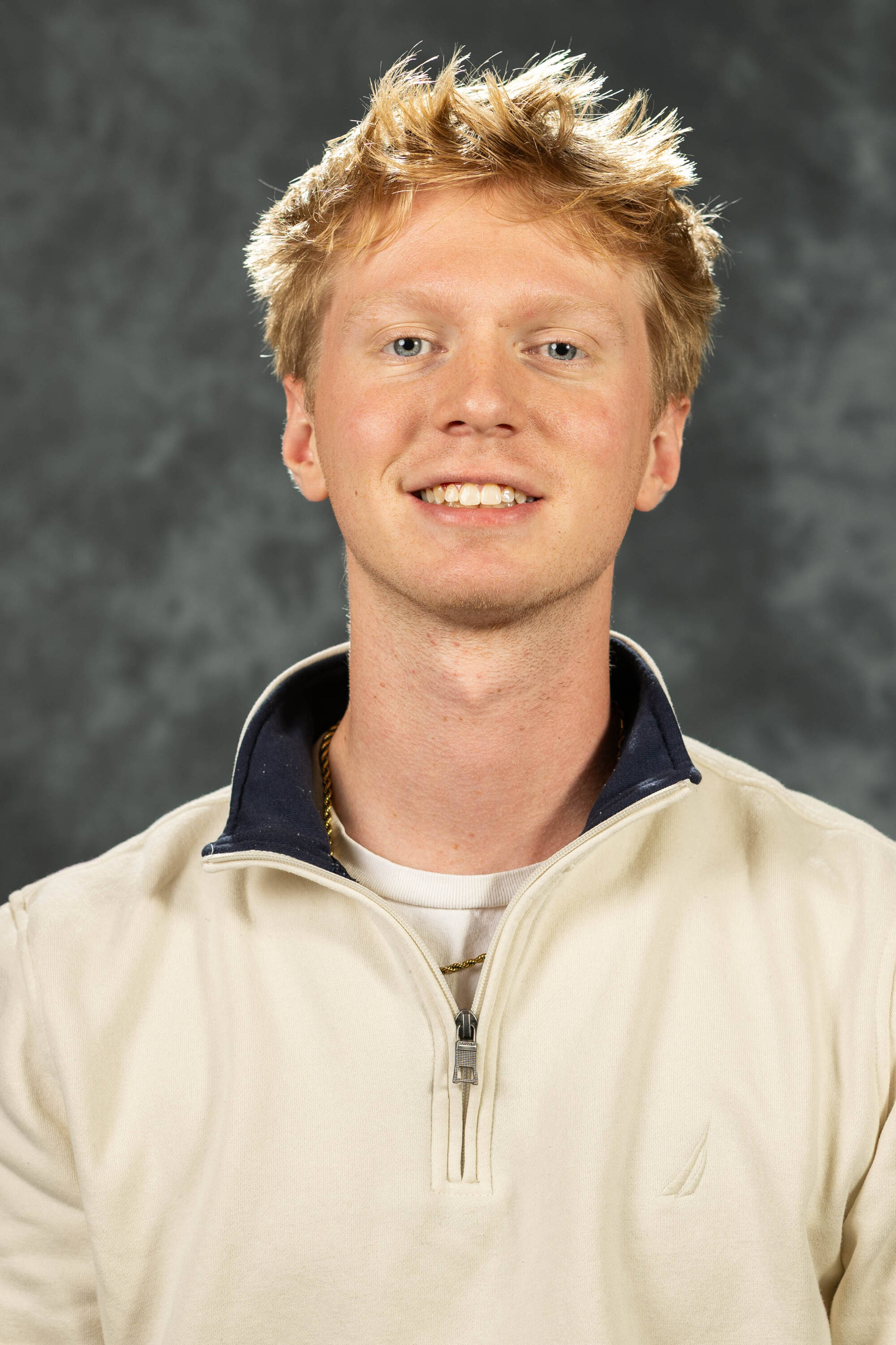 Lukas Hartley smiling in a cream white quarter-zip.